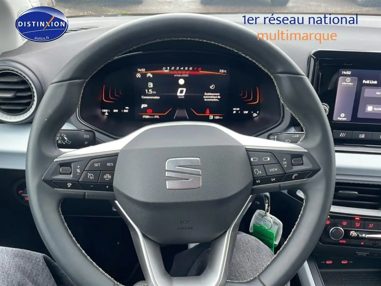 Vue intérieure centrée sur le volant cuir noir avec logo SEAT, tableau de bord digital et écran tactile du SEAT Arona blanc Nevada.