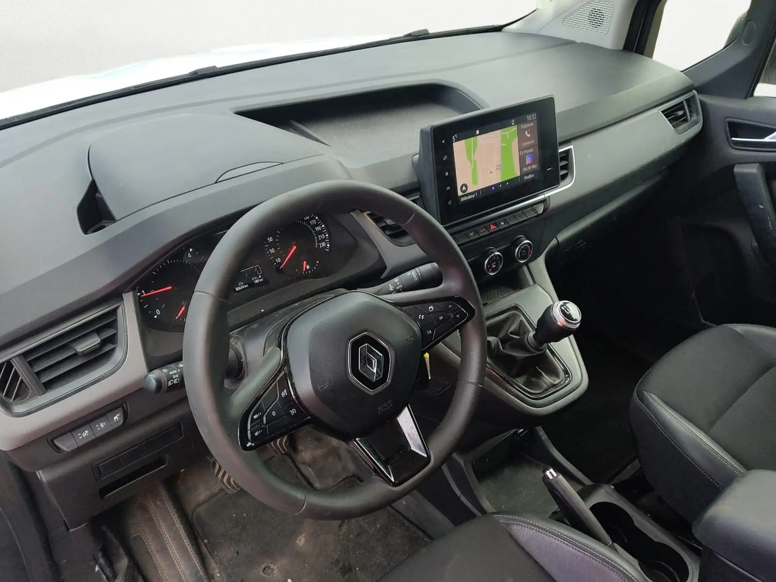 Vue intérieure côté conducteur du Renault Kangoo 2022 avec volant multifonction, boîte manuelle et écran tactile central.