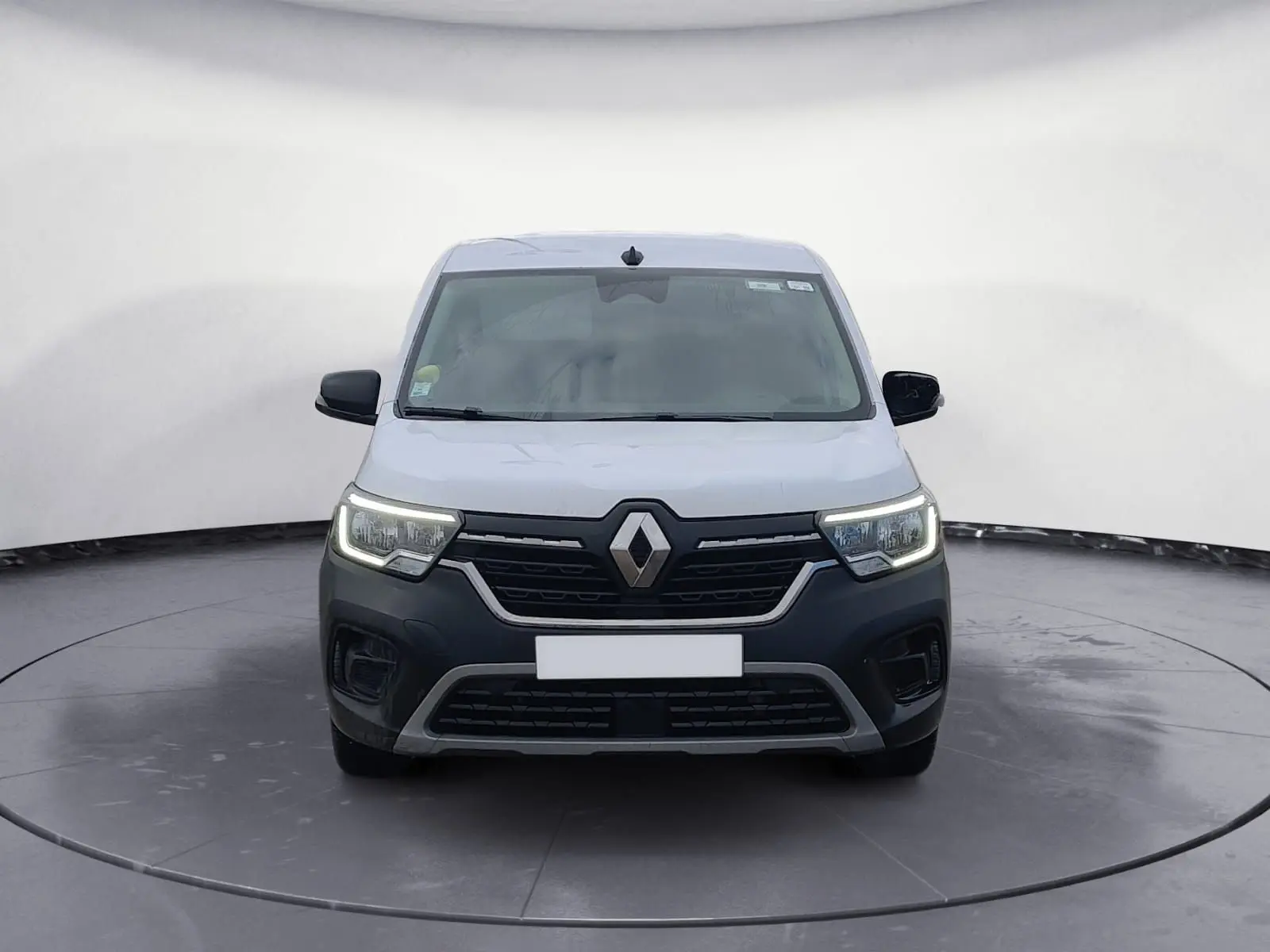 Vue frontale d'un Renault Kangoo blanc 2022 avec calandre noire et phares LED allumés dans un studio.
