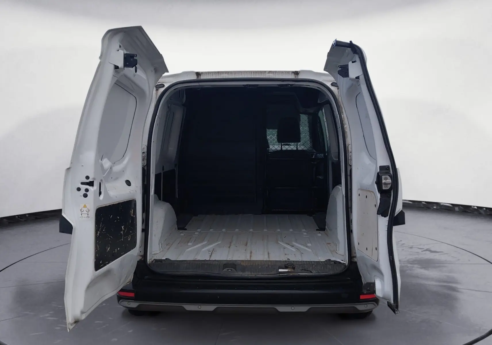 Vue arrière d’un Renault Kangoo blanc 2022 avec portes arrière ouvertes montrant l’espace de chargement vide et cloison pivotante.