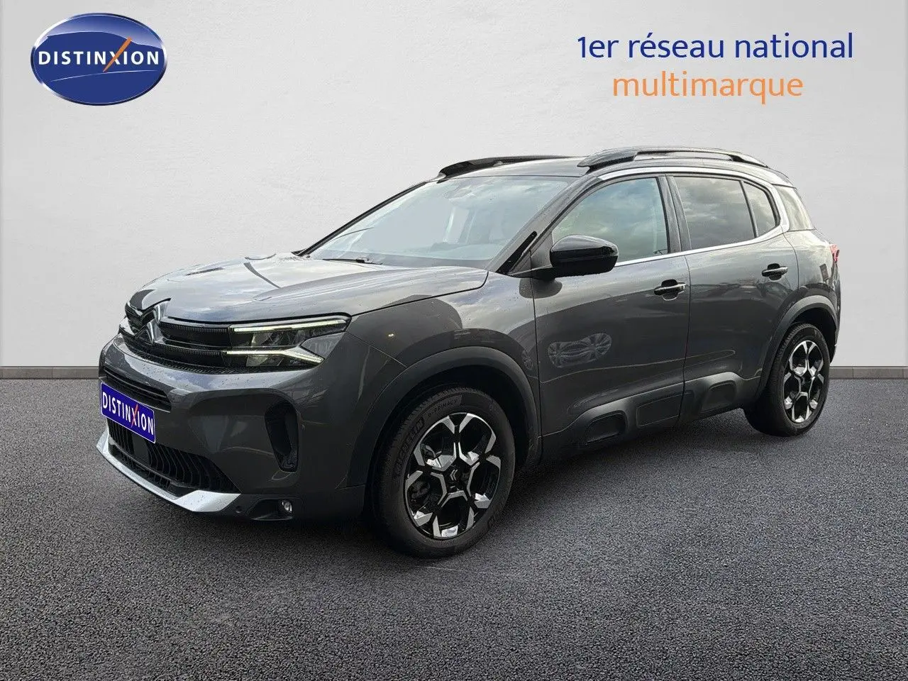 Vue 3/4 avant d'un Citroën C5 Aircross gris platinium métal avec jantes noires et toit ouvrant.