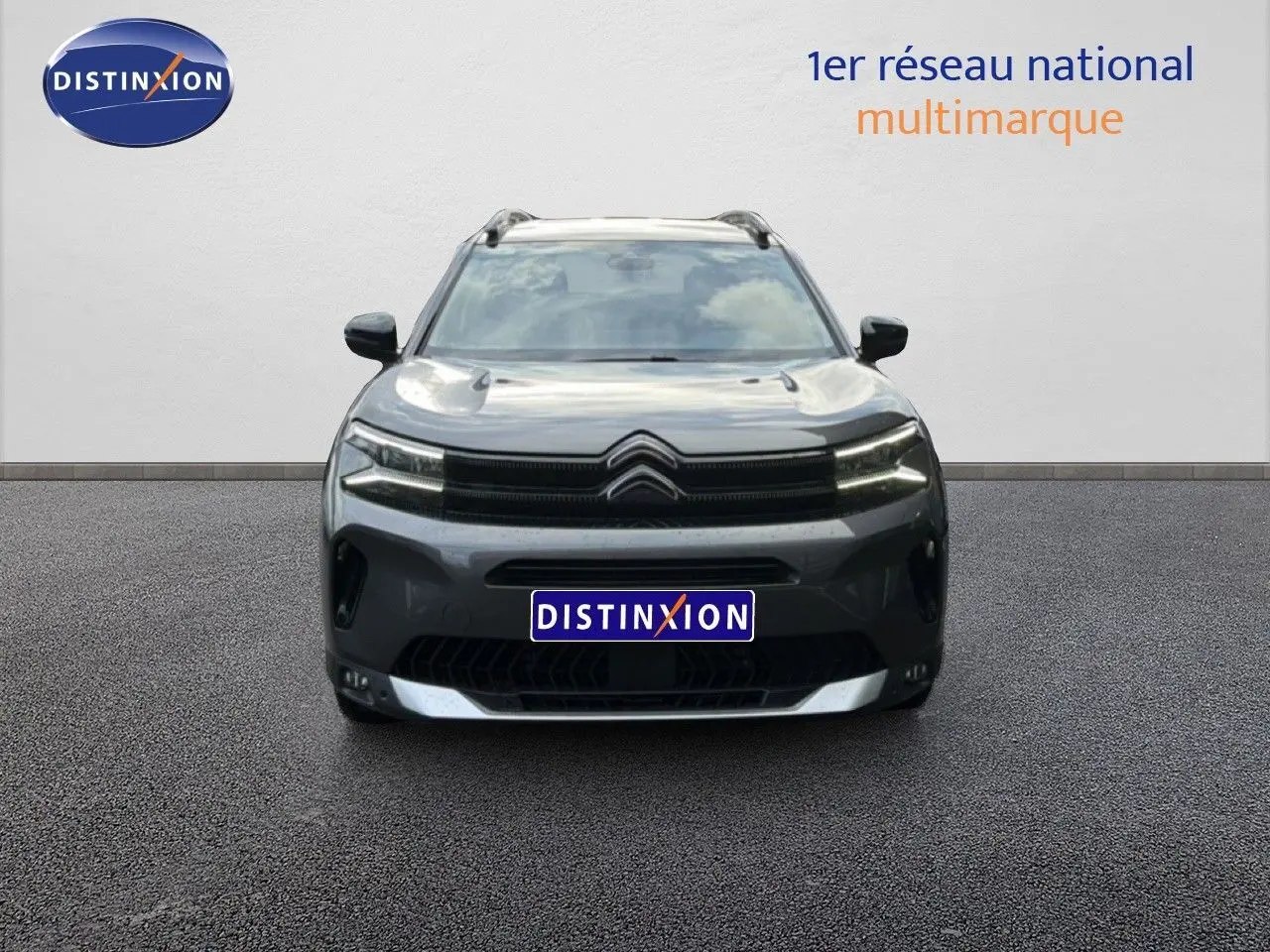 Vue avant d'un Citroën C5 Aircross gris platinium métal 2025 avec calandre noire et phares LED allumés.