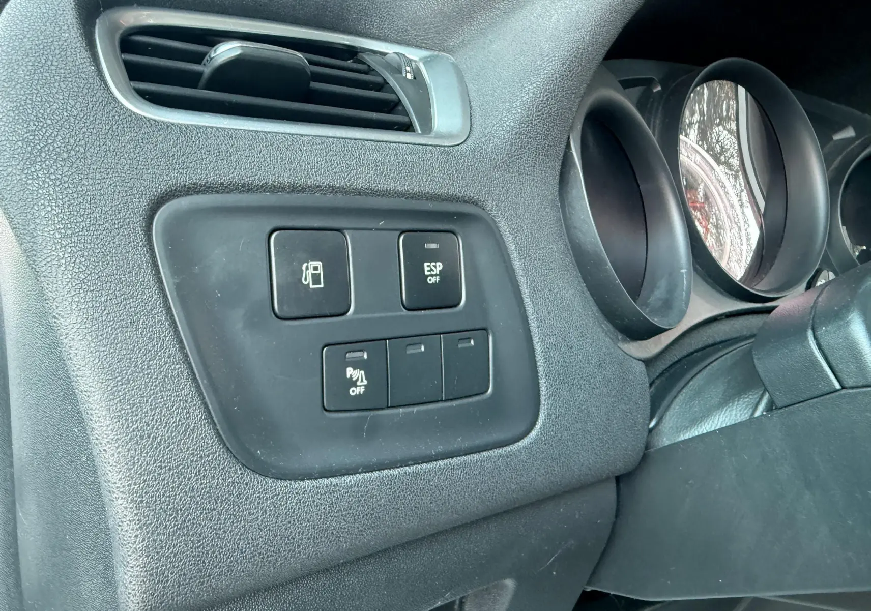 Détail du tableau de bord côté gauche de la Citroën C4 gris, avec commandes ESP et ouverture du réservoir.