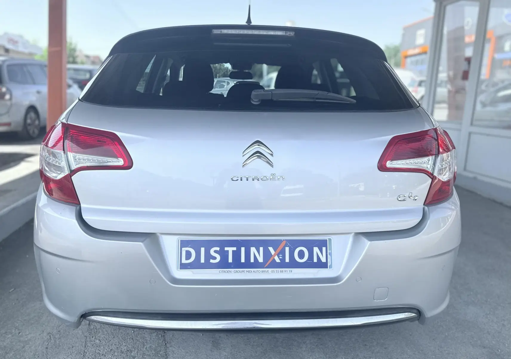 Vue arrière d'une Citroën C4 gris clair, mettant en valeur ses feux arrière et son logo central.