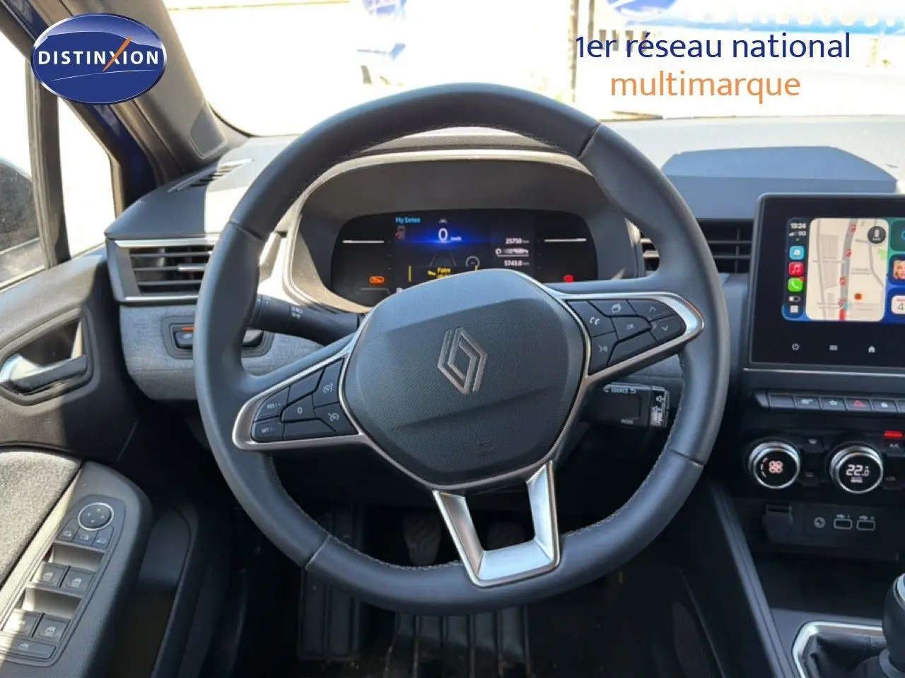 Vue intérieure centrée sur le volant cuir de la Renault Clio 2025, avec tableau de bord digital et écran tactile GPS.