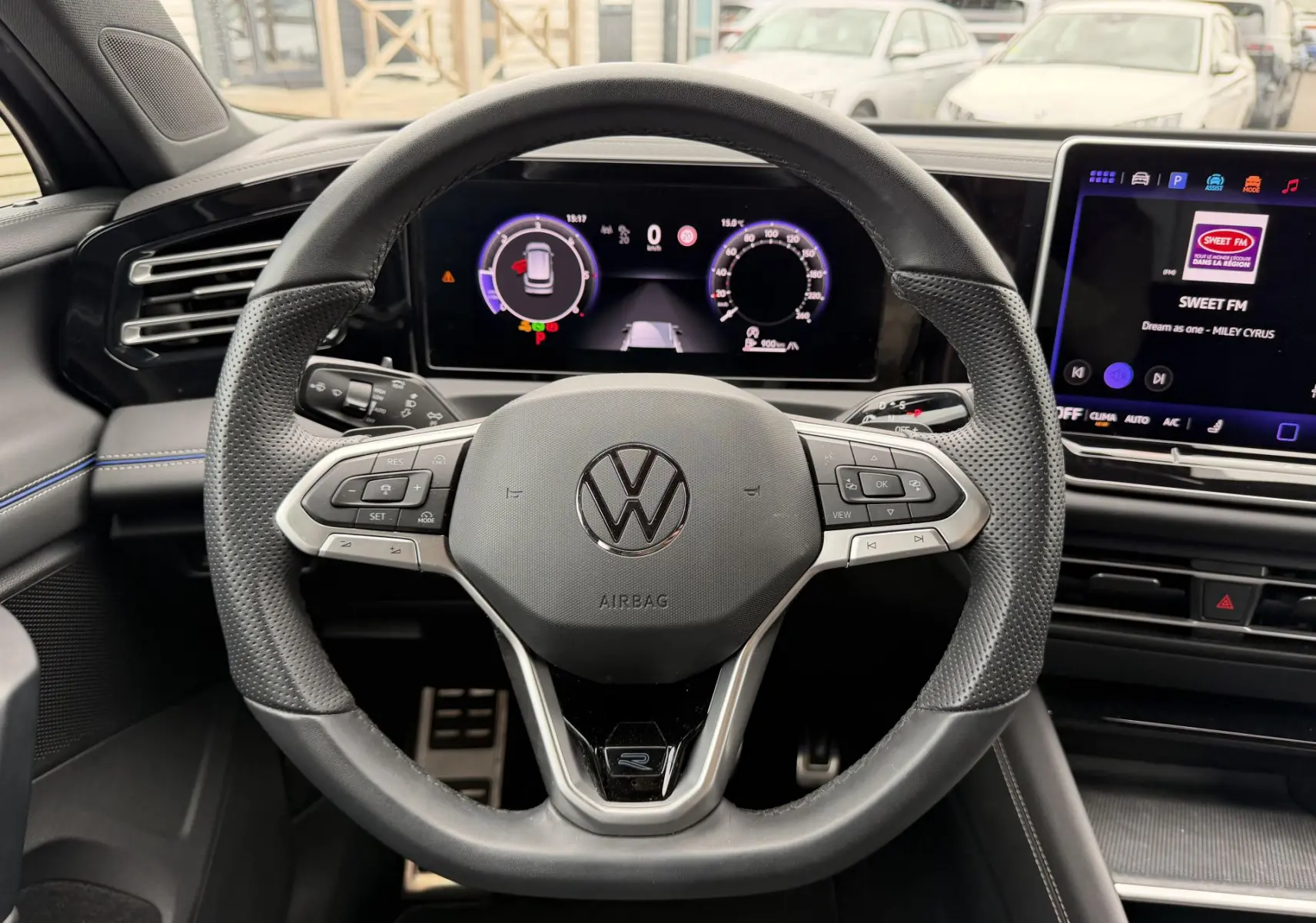 Vue intérieure centrée sur le volant multifonction cuir du Volkswagen Tiguan 2025 avec tableau de bord digital et écran tactile.