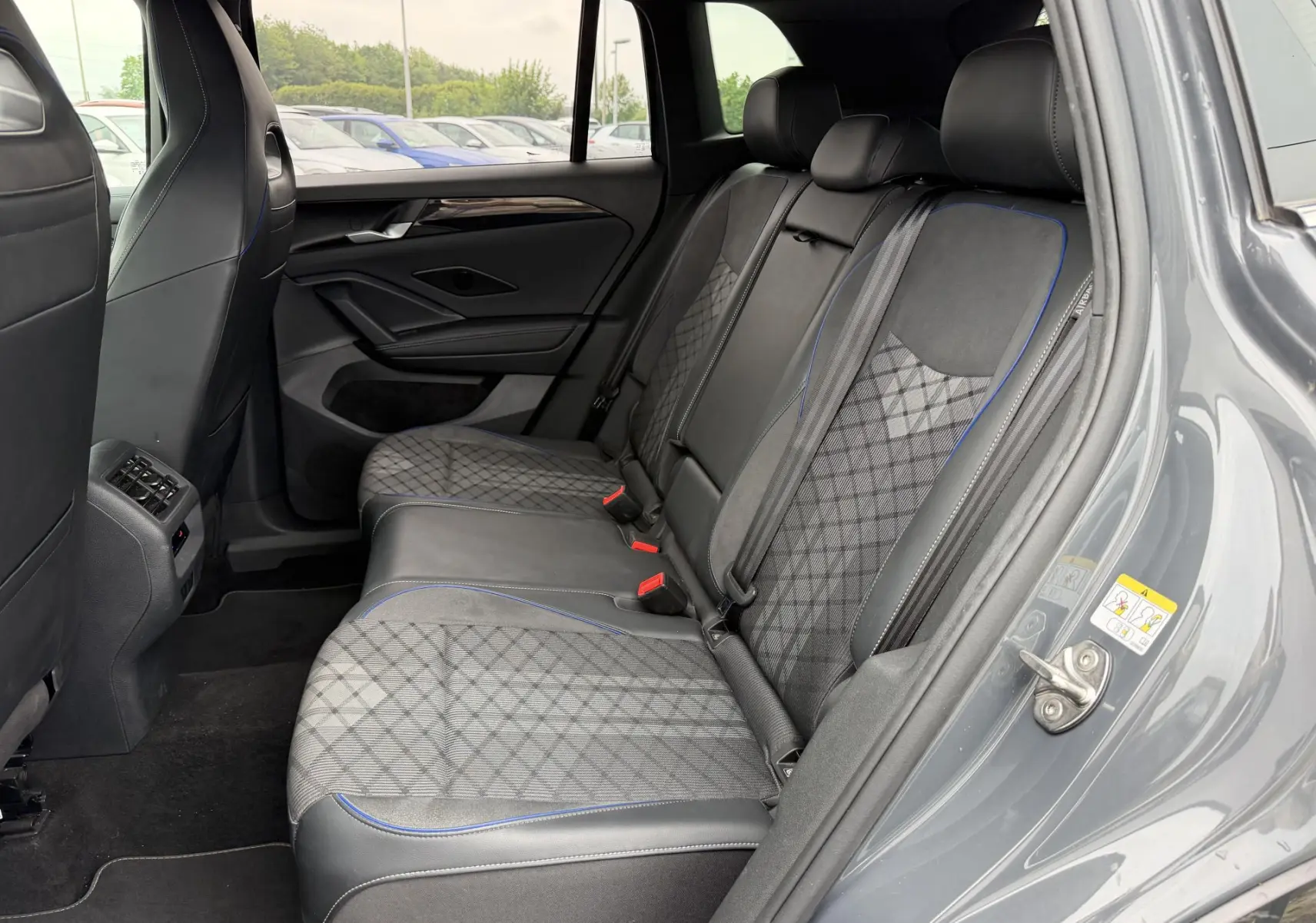 Vue intérieure côté droit des sièges arrière gris avec surpiqûres bleues du Volkswagen Tiguan 2025, porte ouverte.