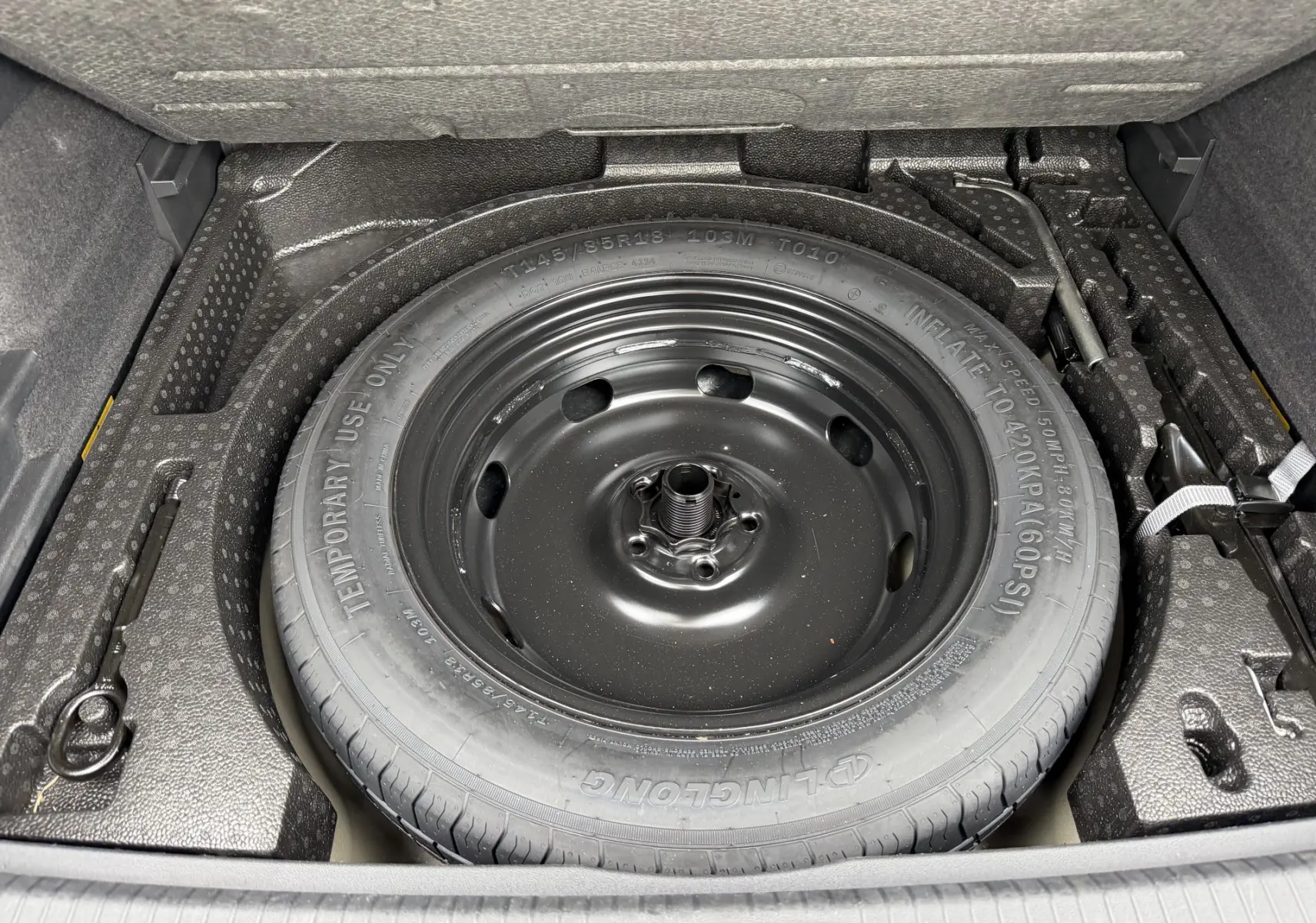 Gros plan sur la roue de secours compacte noire dans le coffre du Volkswagen Tiguan gris 2025.
