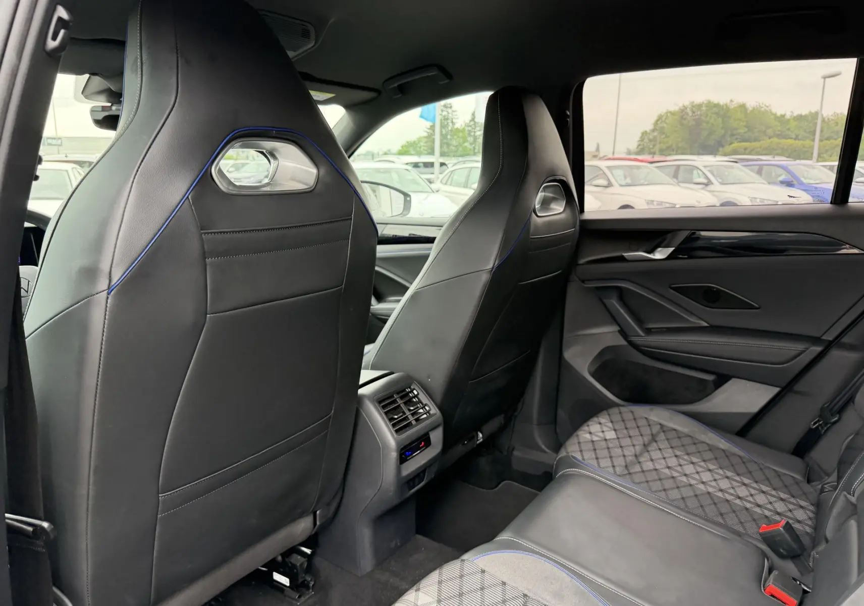 Vue intérieure arrière du Volkswagen Tiguan 2025 avec sièges sport noirs et surpiqûres bleues, ambiance raffinée.