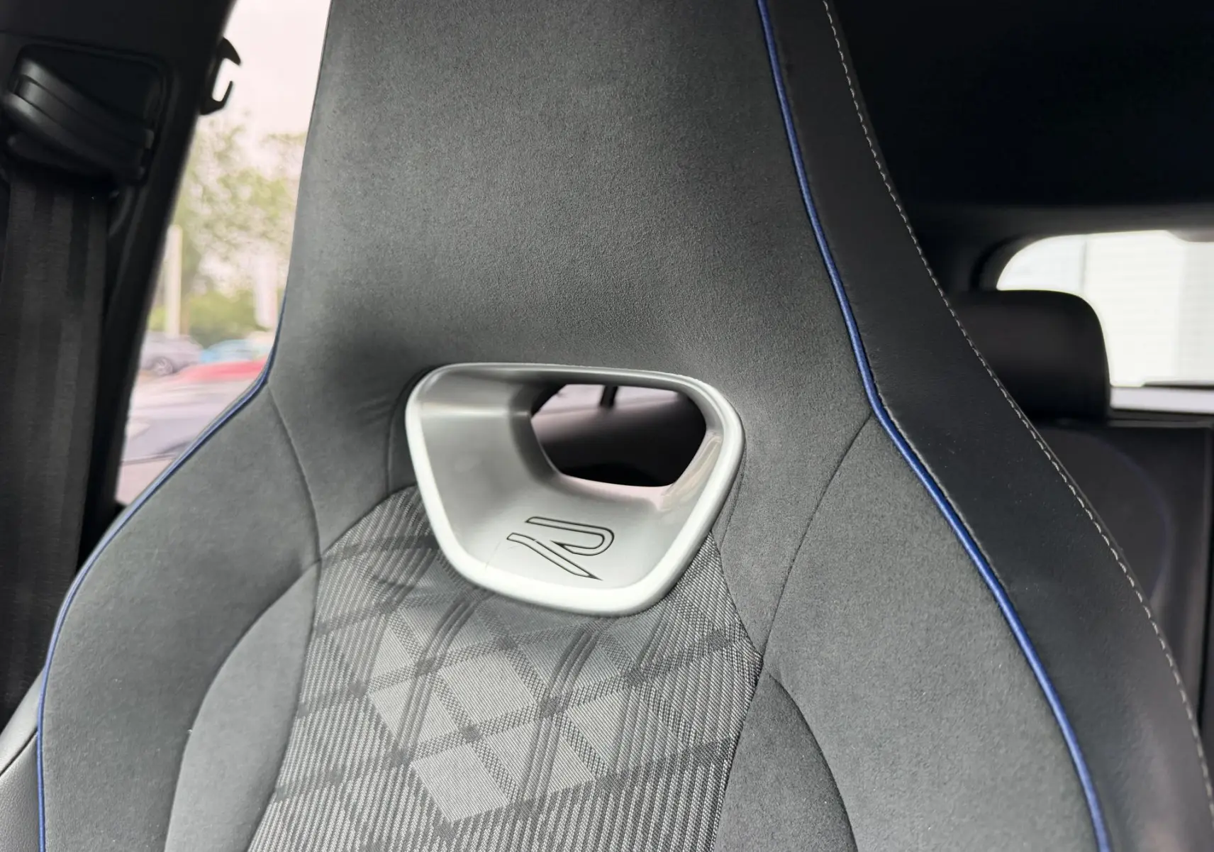 Gros plan sur le siège avant sport gris avec surpiqûres bleues et logo R du Volkswagen Tiguan 2025.