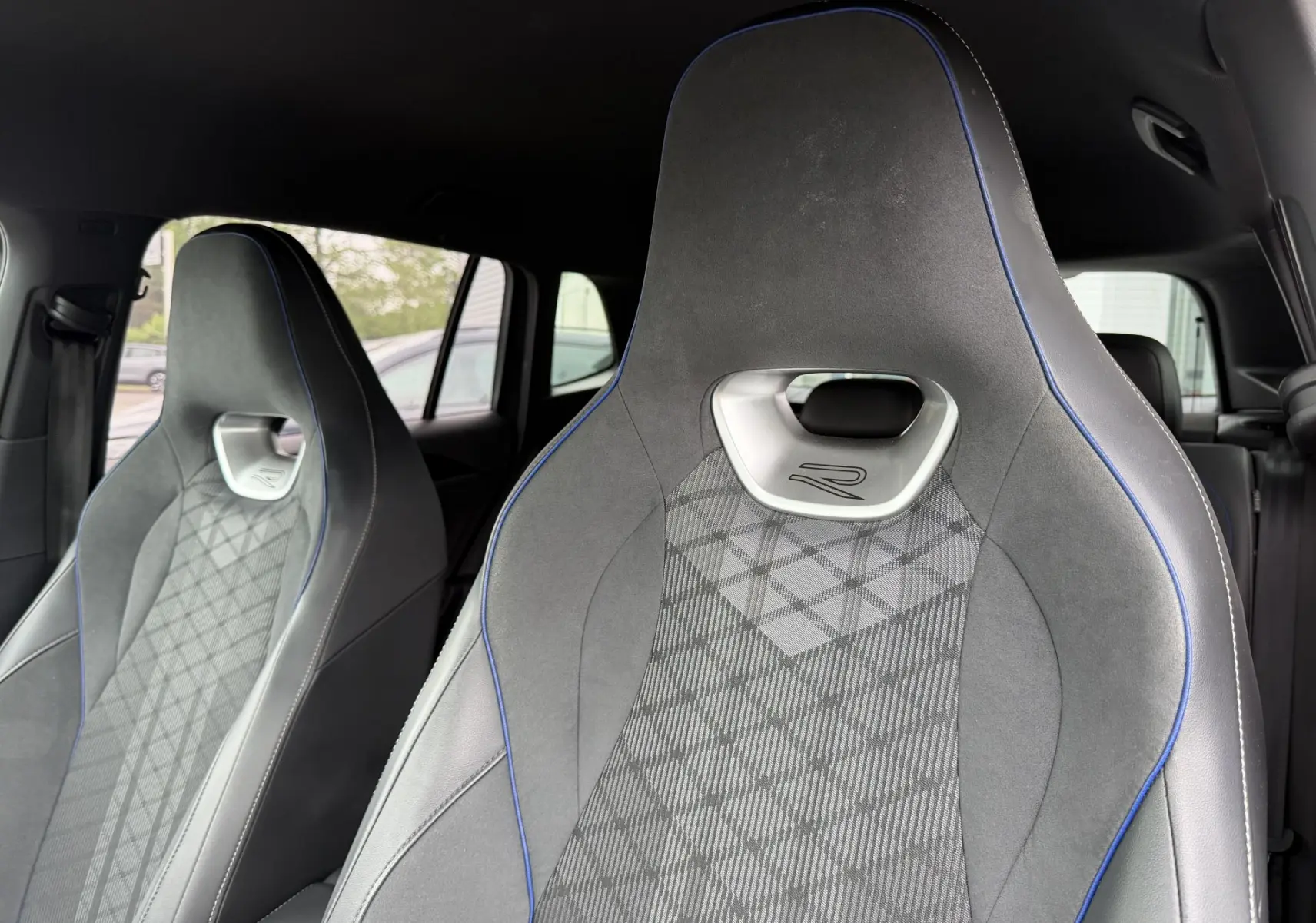 Gros plan sur les sièges avant sport gris avec surpiqûres bleues et logo R du Volkswagen Tiguan 2025.