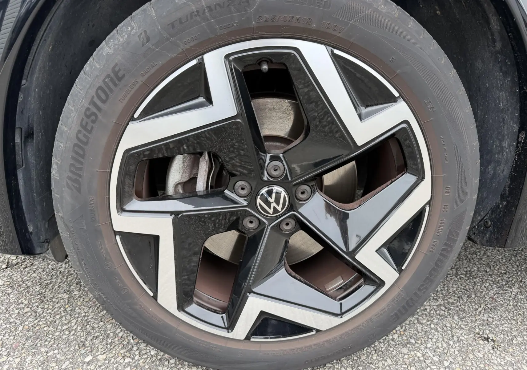 Gros plan sur la jante alliage 19 pouces bicolore noire et argent du Volkswagen Tiguan gris, avec logo VW central.