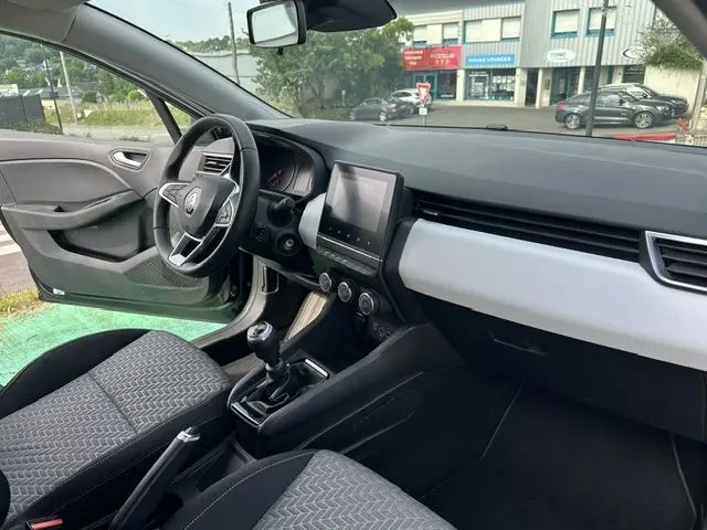 Vue intérieure côté conducteur de la Renault Clio noire 2022, avec tableau de bord moderne et boîte manuelle visible.