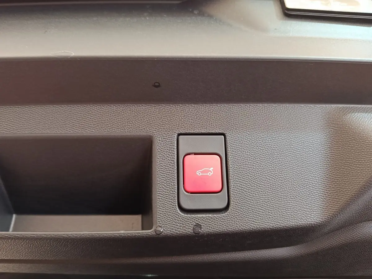 Bouton rouge d'ouverture électrique du coffre sur panneau intérieur noir d'une Citroën C5 Hybride 2026.