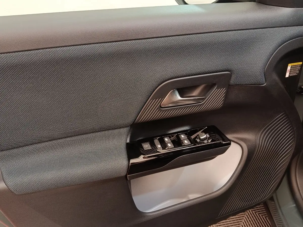 Gros plan sur la porte intérieure côté conducteur de la Citroën C5 hybride 2026, avec commandes de vitres et poignée noire.