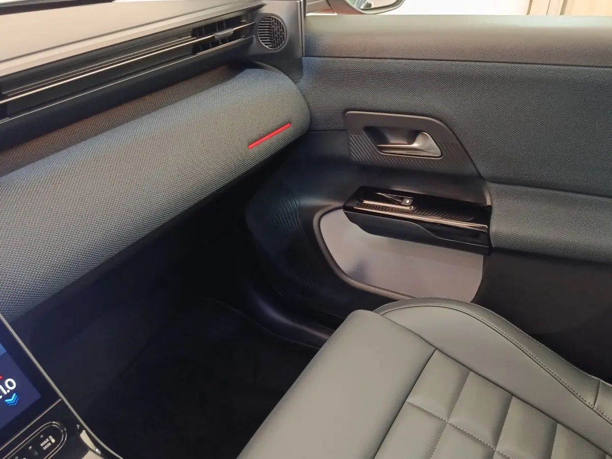 Vue intérieure côté passager avant du Citroën C5 Hybride 2026, avec sellerie grise et détails noirs texturés.