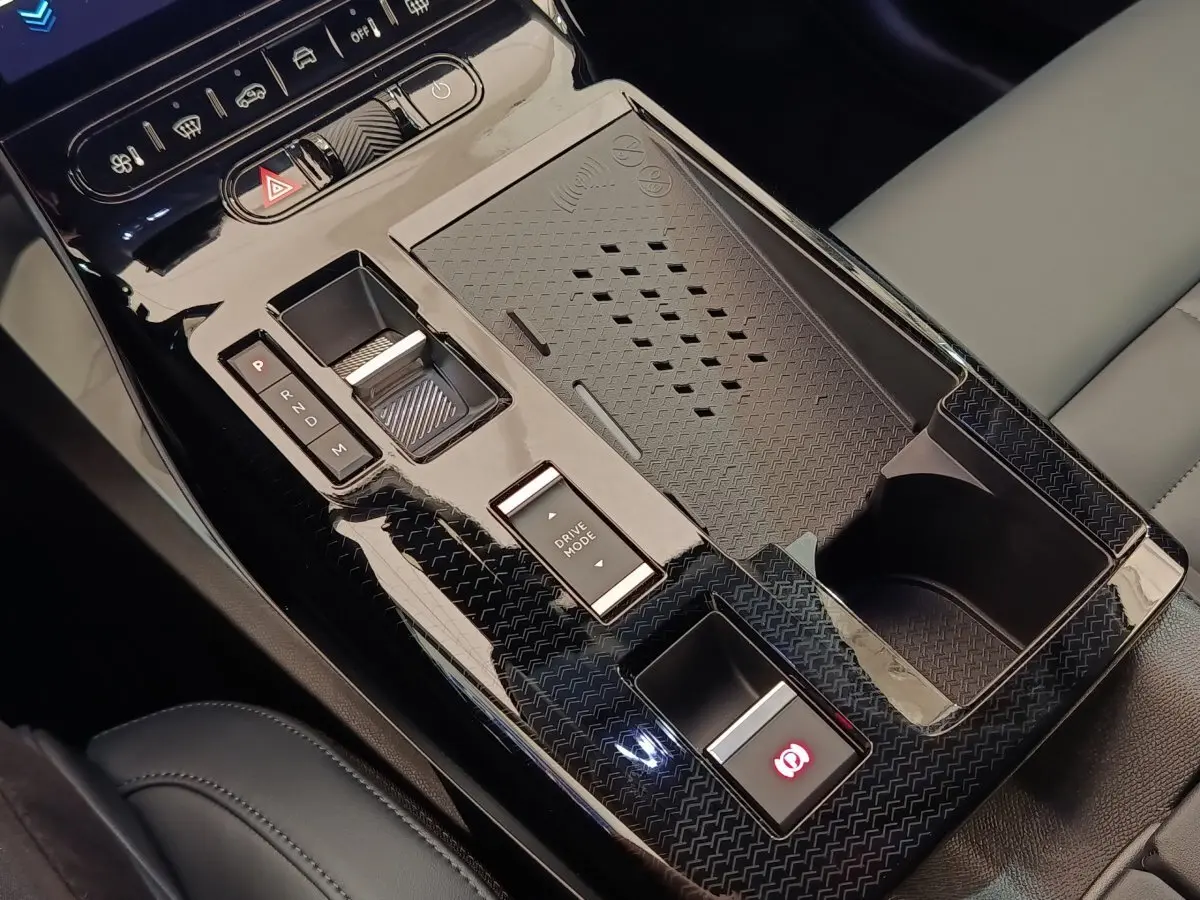 Gros plan sur la console centrale noire brillante du Citroën C5 Hybride 2026 avec commandes de boîte auto et recharge sans fil.