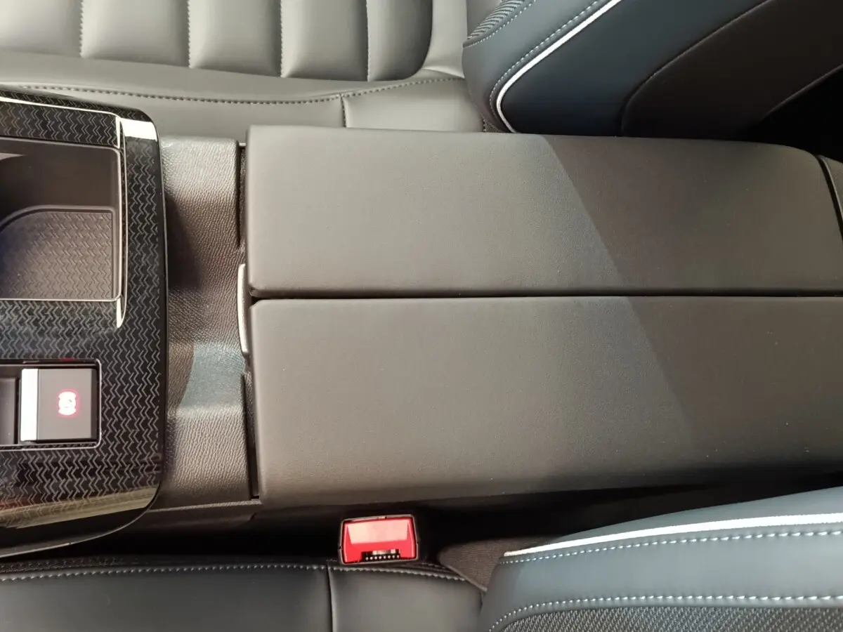 Gros plan sur l'accoudoir central noir et la console centrale avec bouton frein électrique dans l'habitacle d'une Citroën C5.