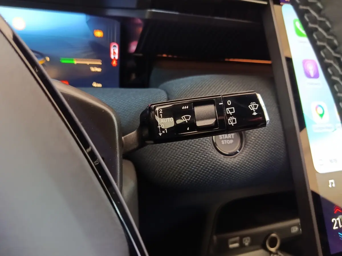 Gros plan sur la commande d’essuie-glace noire et le bouton start/stop dans l’habitacle sombre du Citroën C5 Hybride 2026.