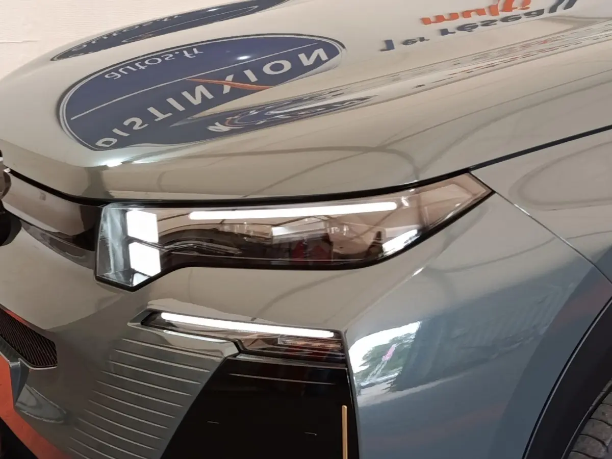 Gros plan sur l'avant droit vert métallisé du Citroën C5 Hybride 145ch avec phares LED et calandre distinctive.