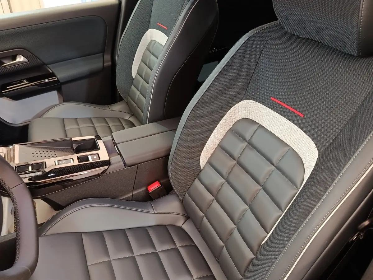 Vue intérieure rapprochée des sièges avant en cuir noir et tissu gris avec surpiqûres rouges d'une Citroën C5 Hybride.