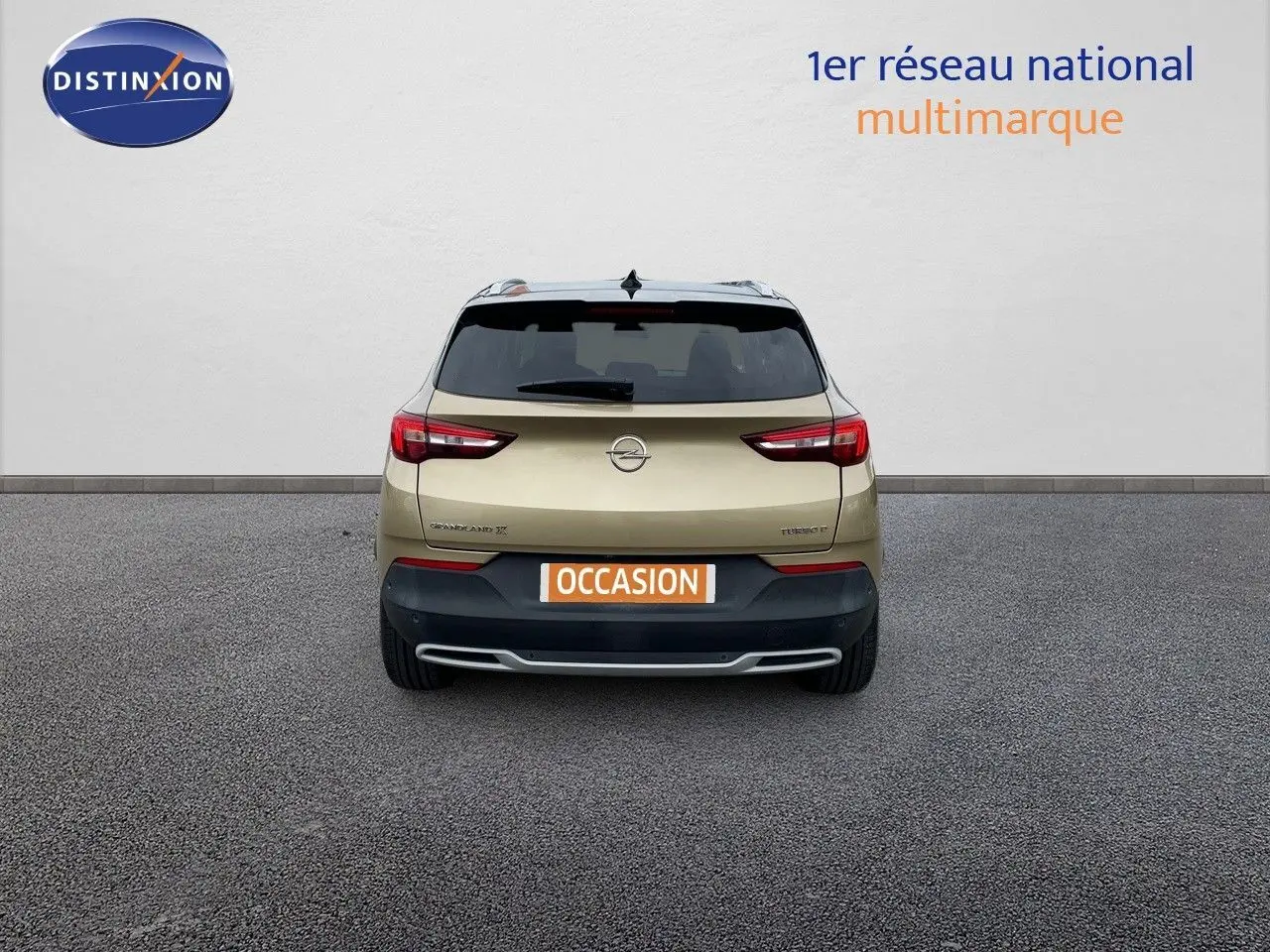 Vue arrière d'un Opel Grandland X diesel couleur golden sunstone metal avec plaque occasion sur un sol gris.