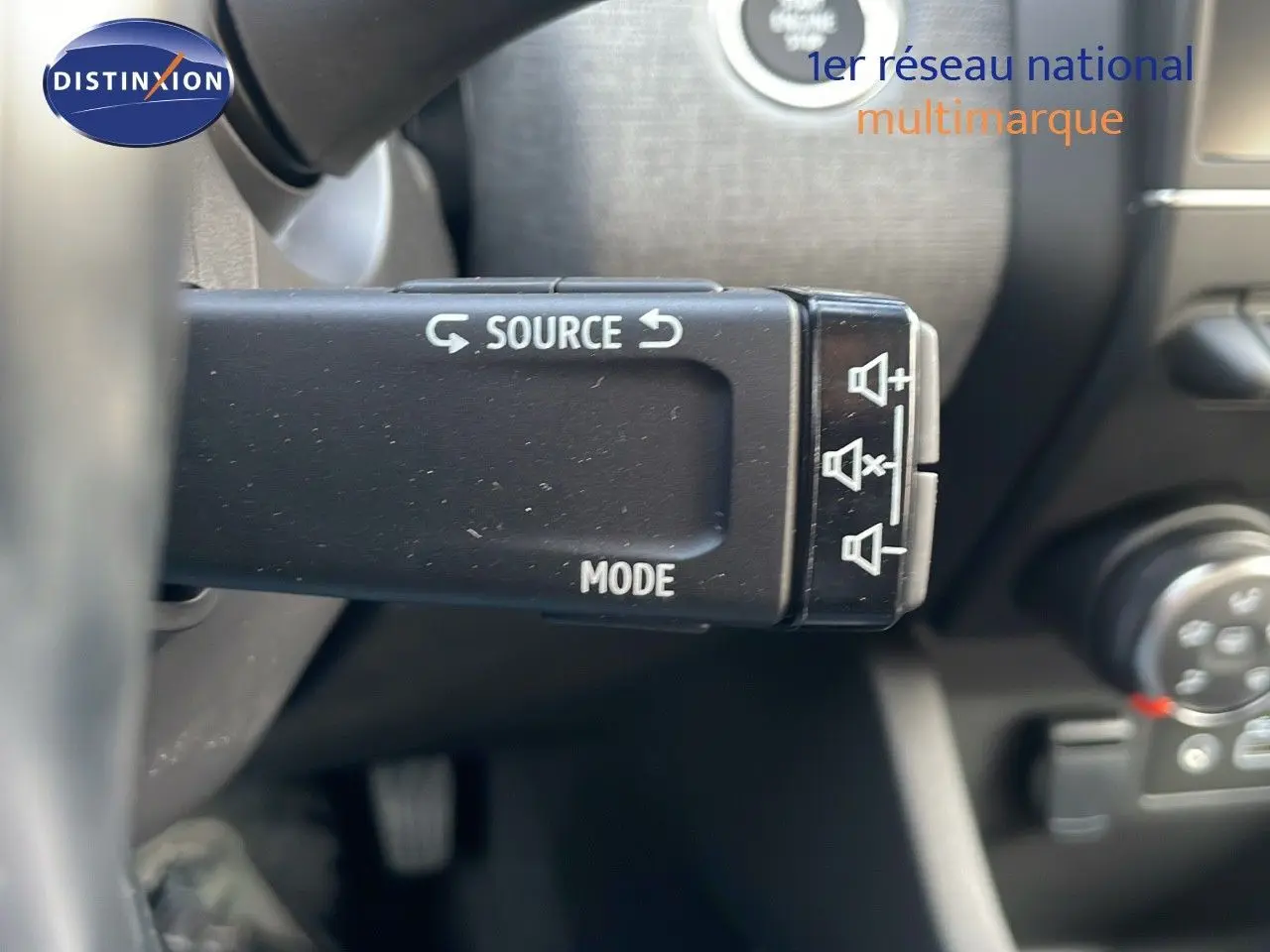 Gros plan sur la commande au volant de la Renault Clio 1.5 DCI 100CH Evolution, boutons source et mode visibles.