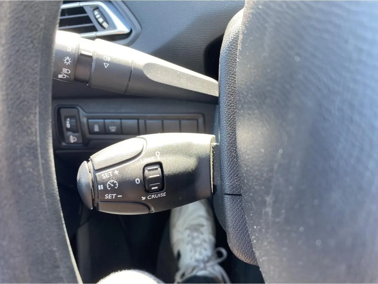 Gros plan sur la commande de régulateur de vitesse à gauche du volant dans l'habitacle d'une Peugeot 308 SW.