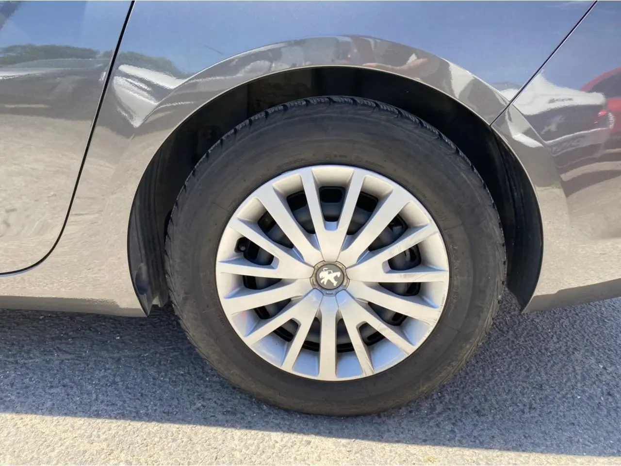 Gros plan sur la roue arrière droite gris clair d'une Peugeot 308 SW 1.6 BlueHDi de 2017 avec jante en alliage.