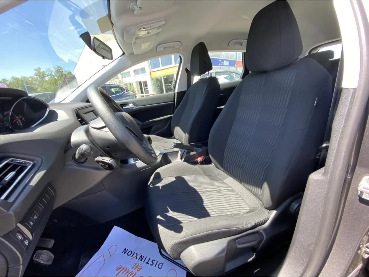 Intérieur avant droit de la Peugeot 308 SW 2017, sièges tissu noir et tableau de bord visible au soleil.