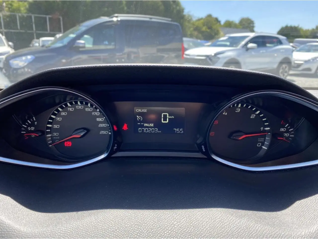 Vue rapprochée du tableau de bord numérique d'une Peugeot 308 SW gris clair, affichant 70 203 km et vitesse à zéro.