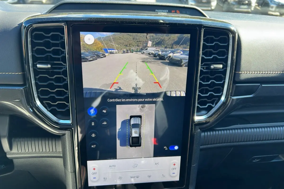 Vue rapprochée de l'écran central tactile du Ford Ranger 2025 bleu lightning montrant la caméra de recul et les aides au stationnement.