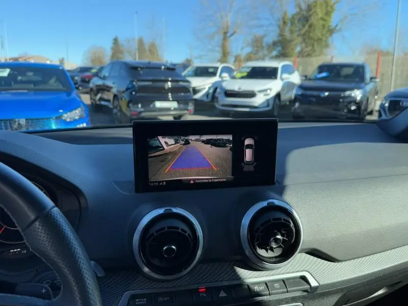 Vue intérieure du tableau de bord de l'Audi Q2 noir Mythic, avec écran de caméra de recul affiché en plein jour.