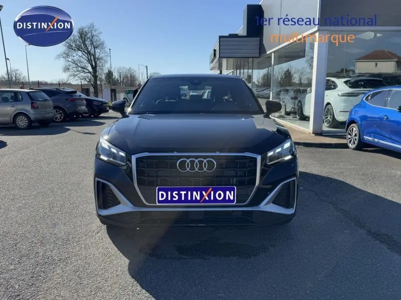 Vue frontale d'un Audi Q2 30 TDI S line noir Mythic métallisé, avec calandre hexagonale et phares LED allumés.