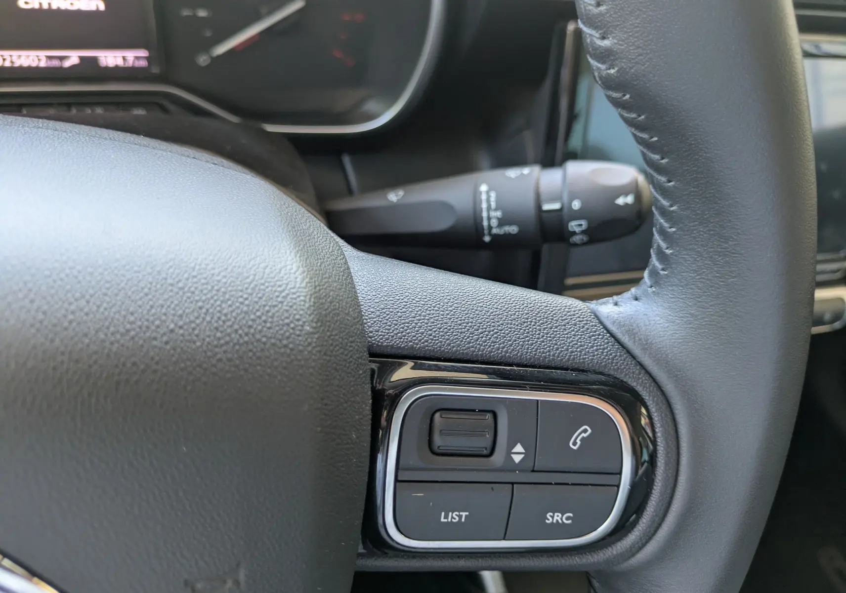 Gros plan sur les commandes gauche du volant en cuir noir du Citroën C3 Aircross 2024, boutons de volume et appel.