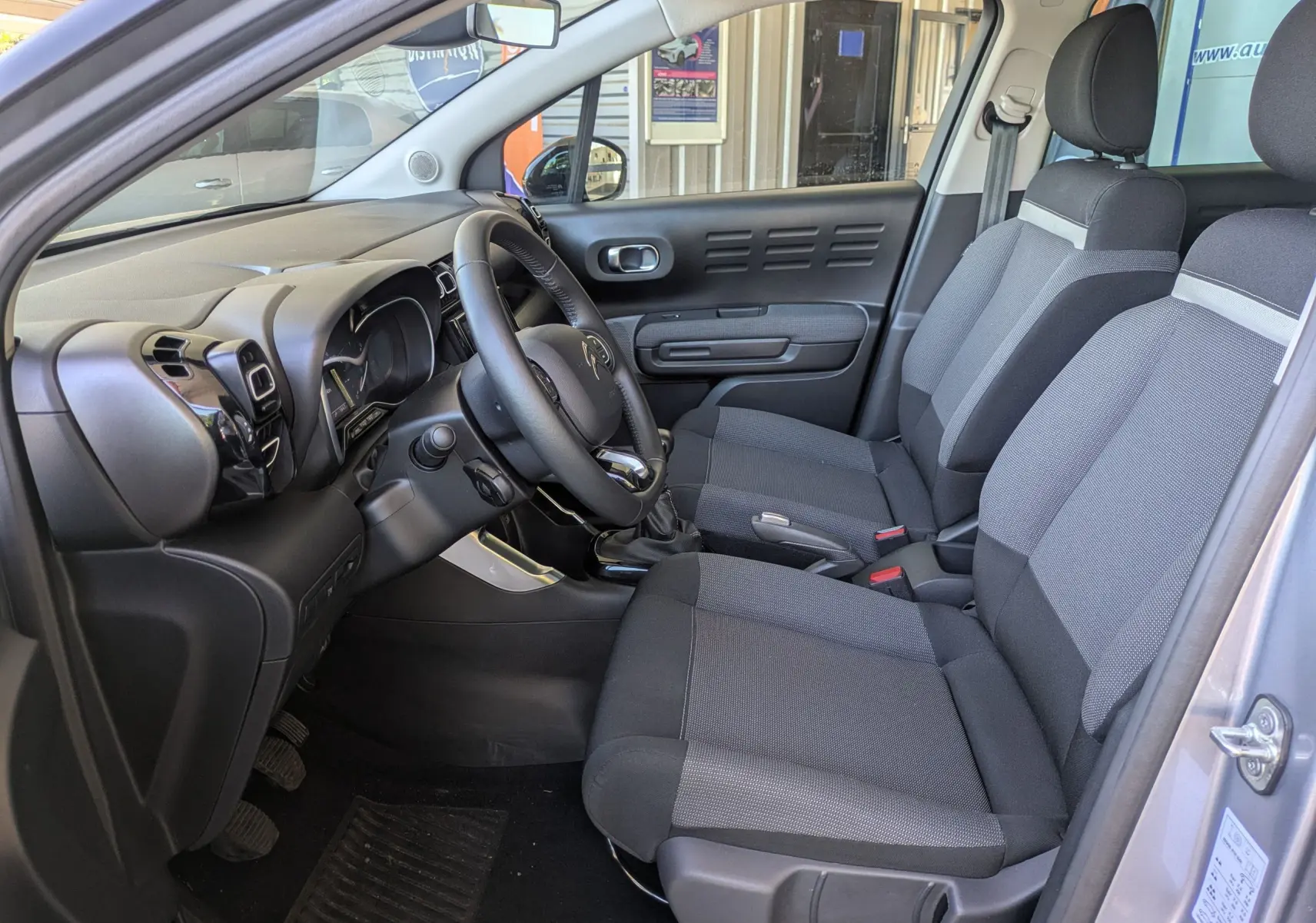 Détail des commandes électriques des vitres et rétroviseurs sur la porte côté conducteur d'une Citroën C3 Aircross gris Artense.