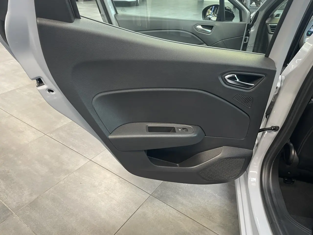 Vue intérieure de la porte arrière gauche gris rafale de la Renault Clio 1.5 Blue dCi 2025 avec commande de vitre électrique.