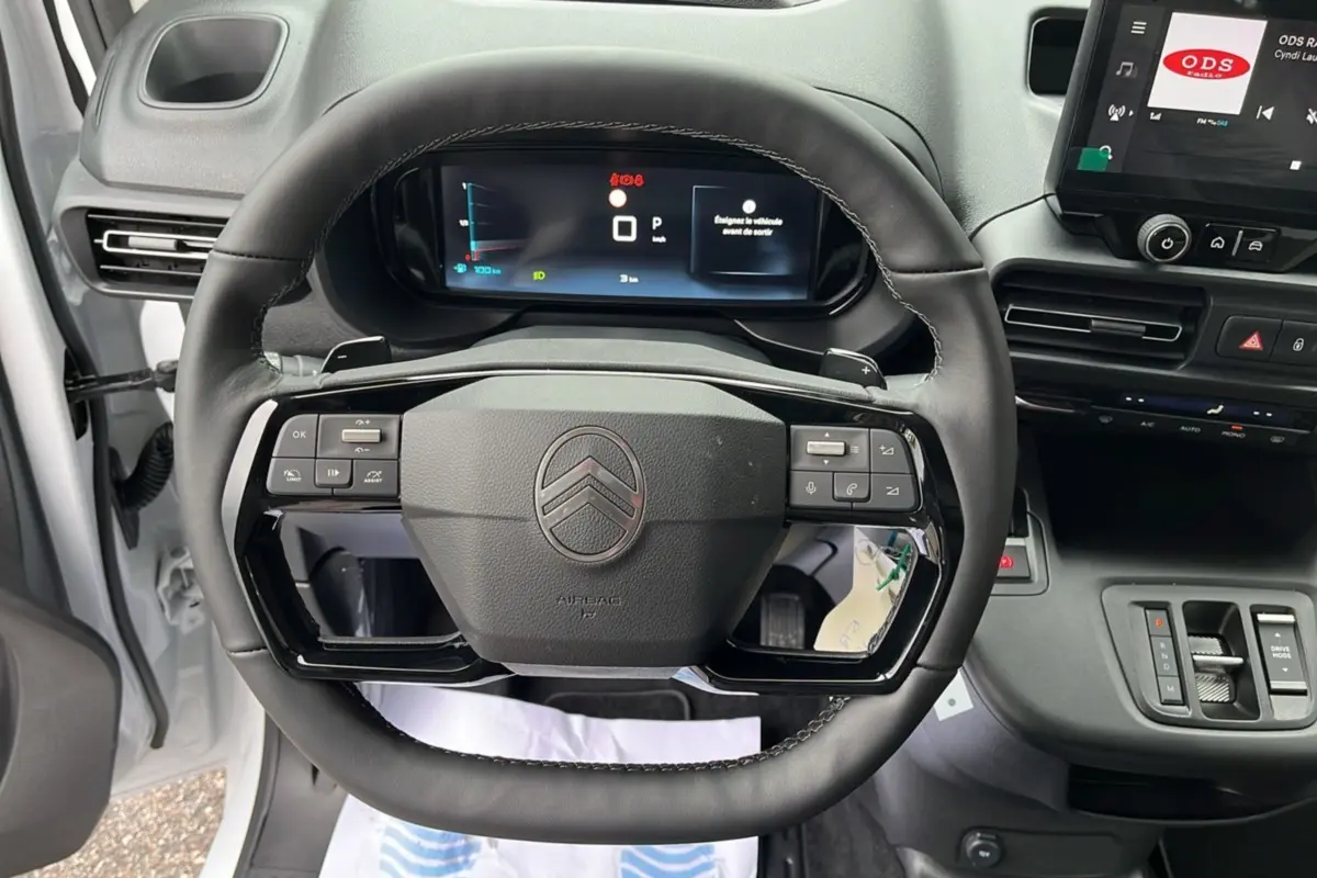 Vue rapprochée du volant cuir multifonctions noir du Citroën Berlingo Kaolin White 2025 avec tableau de bord digital.