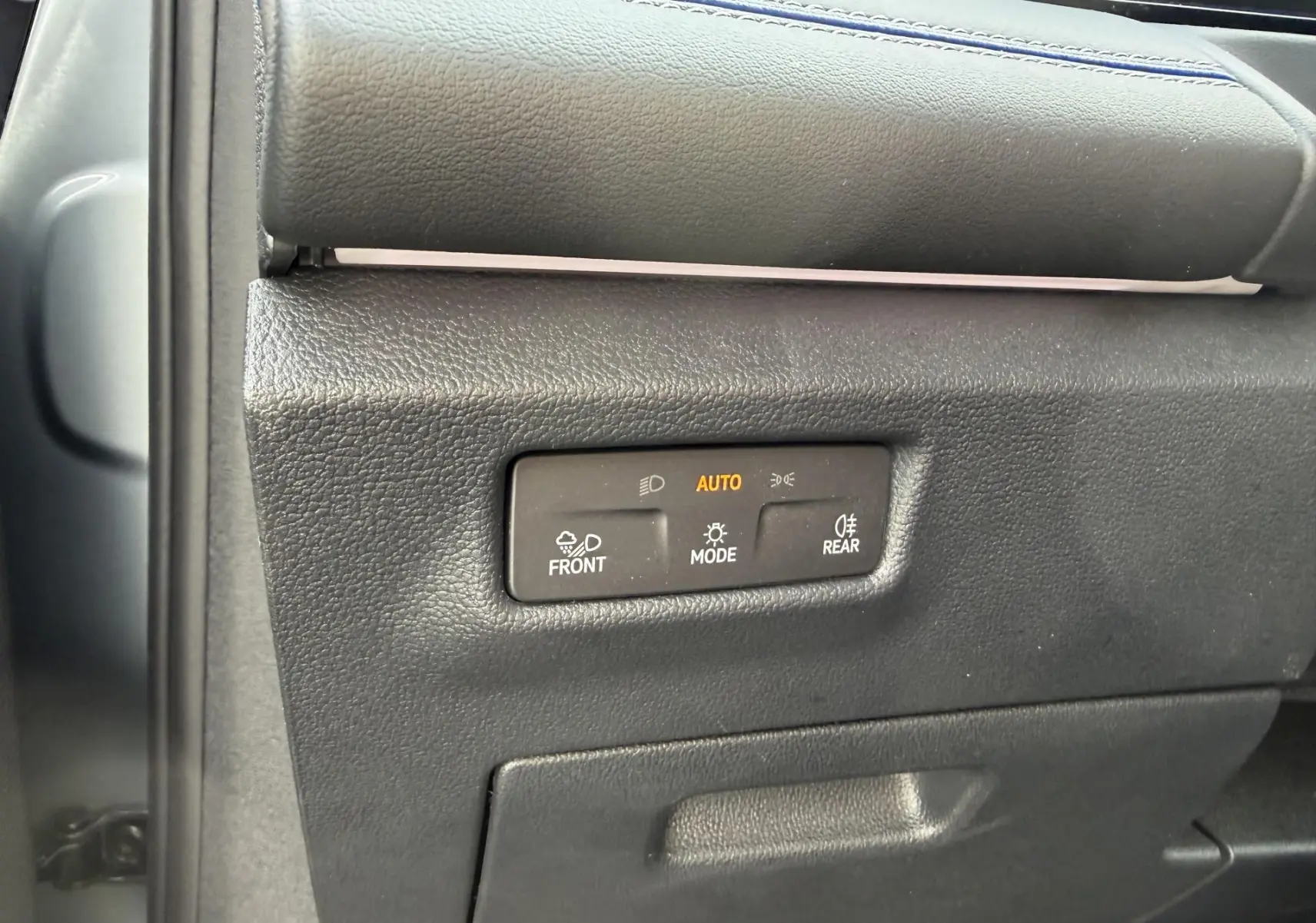 Gros plan sur les commandes d’éclairage à gauche du tableau de bord du Volkswagen Tiguan gris 2025.
