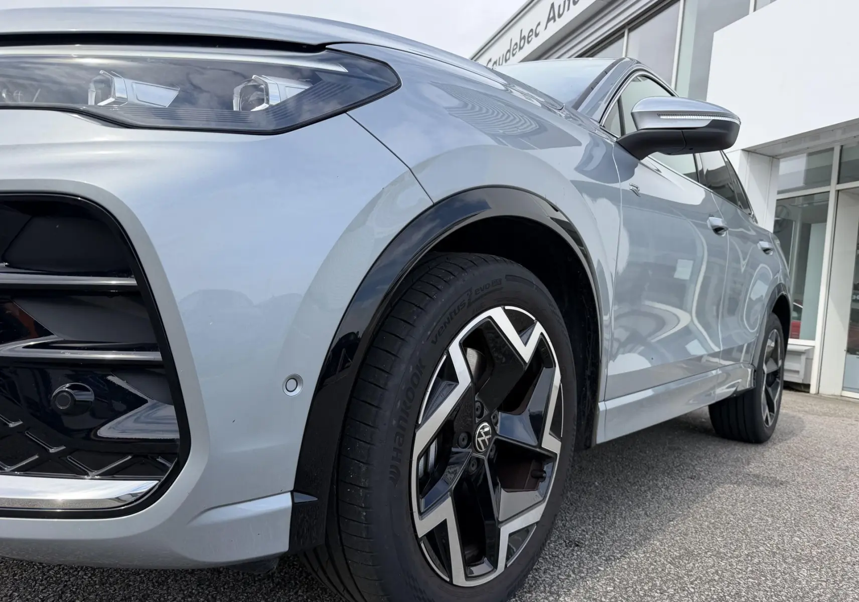 Vue 3/4 avant droit du Volkswagen Tiguan gris, mettant en valeur la jante alliage noire et argentée et le phare LED.