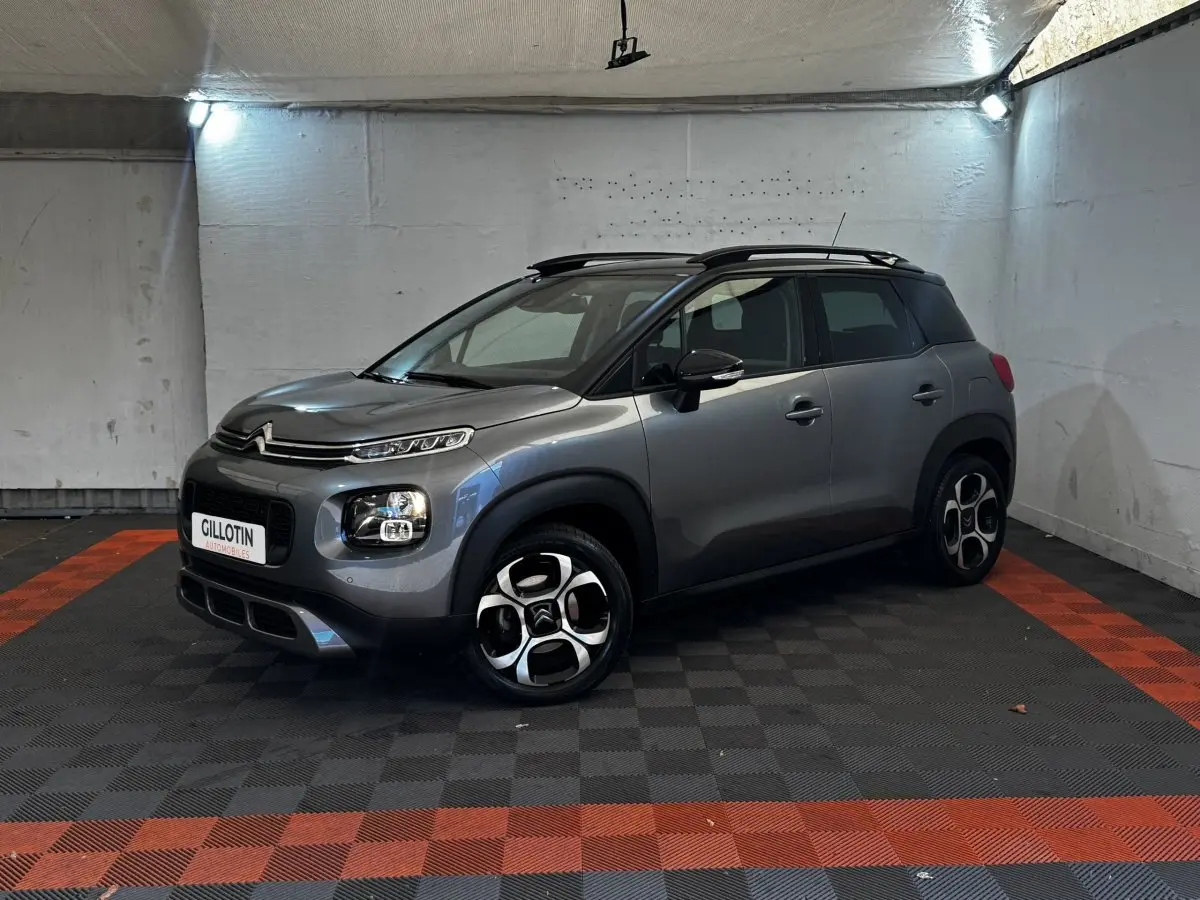 Citroën C3 PureTech 110 gris foncé en 3/4 avant droit, avec toit noir et jantes distinctives en alliage.