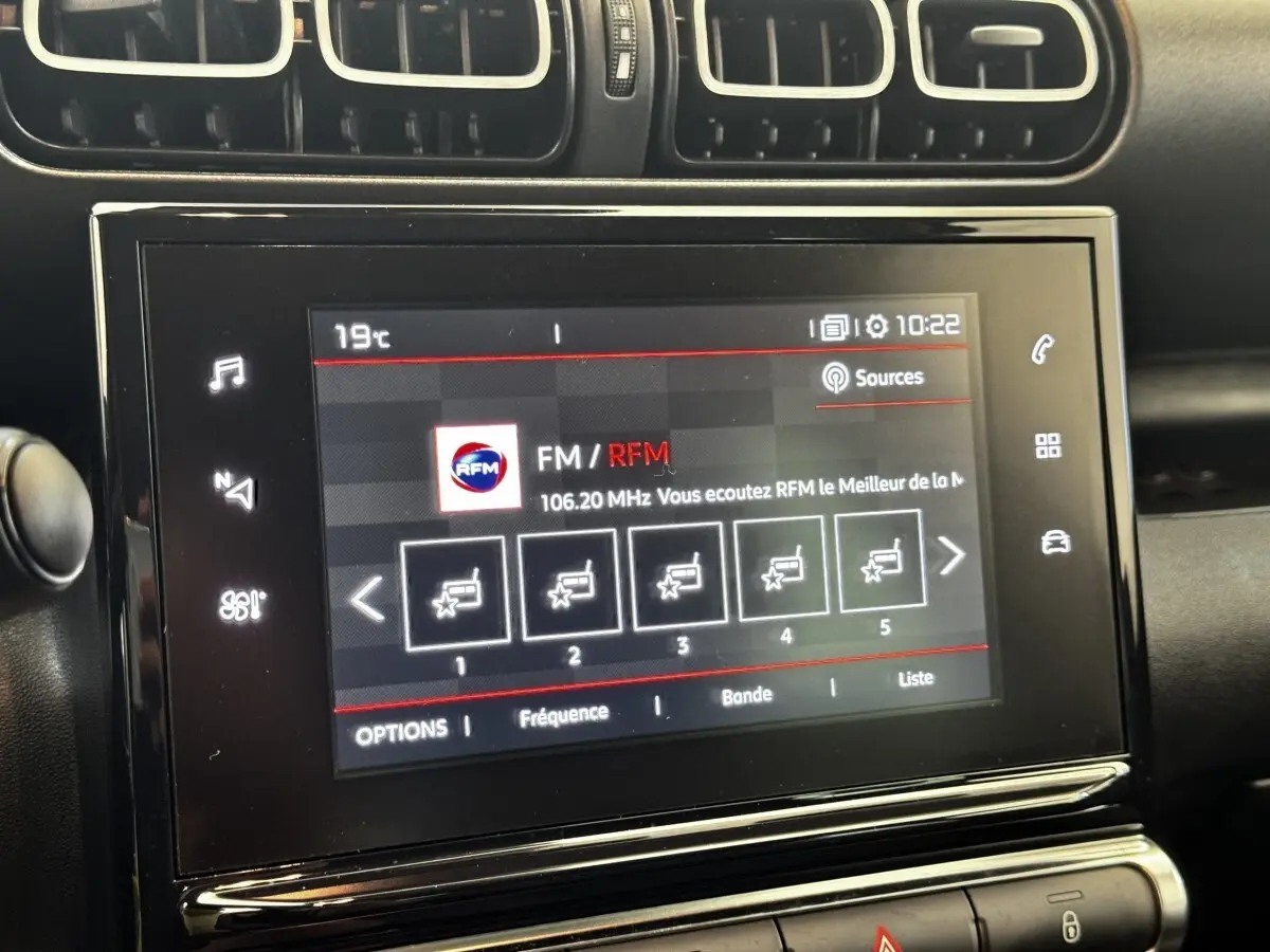 Écran tactile central de la Citroën C3 gris foncé, affichant la radio FM avec commandes tactiles et aérateurs supérieurs.
