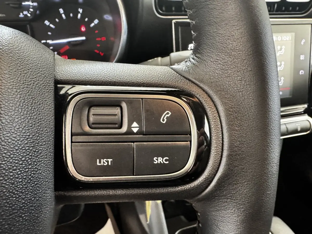 Gros plan sur le volant cuir noir de la Citroën C3 2019 avec commandes multifonctions et tableau de bord partiellement visible.