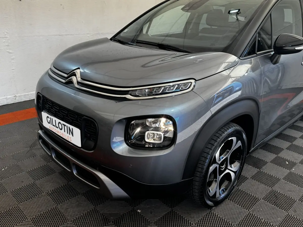 Vue 3/4 avant droit d'une Citroën C3 PureTech 110 gris foncé avec phares LED et jantes bicolores distinctives.