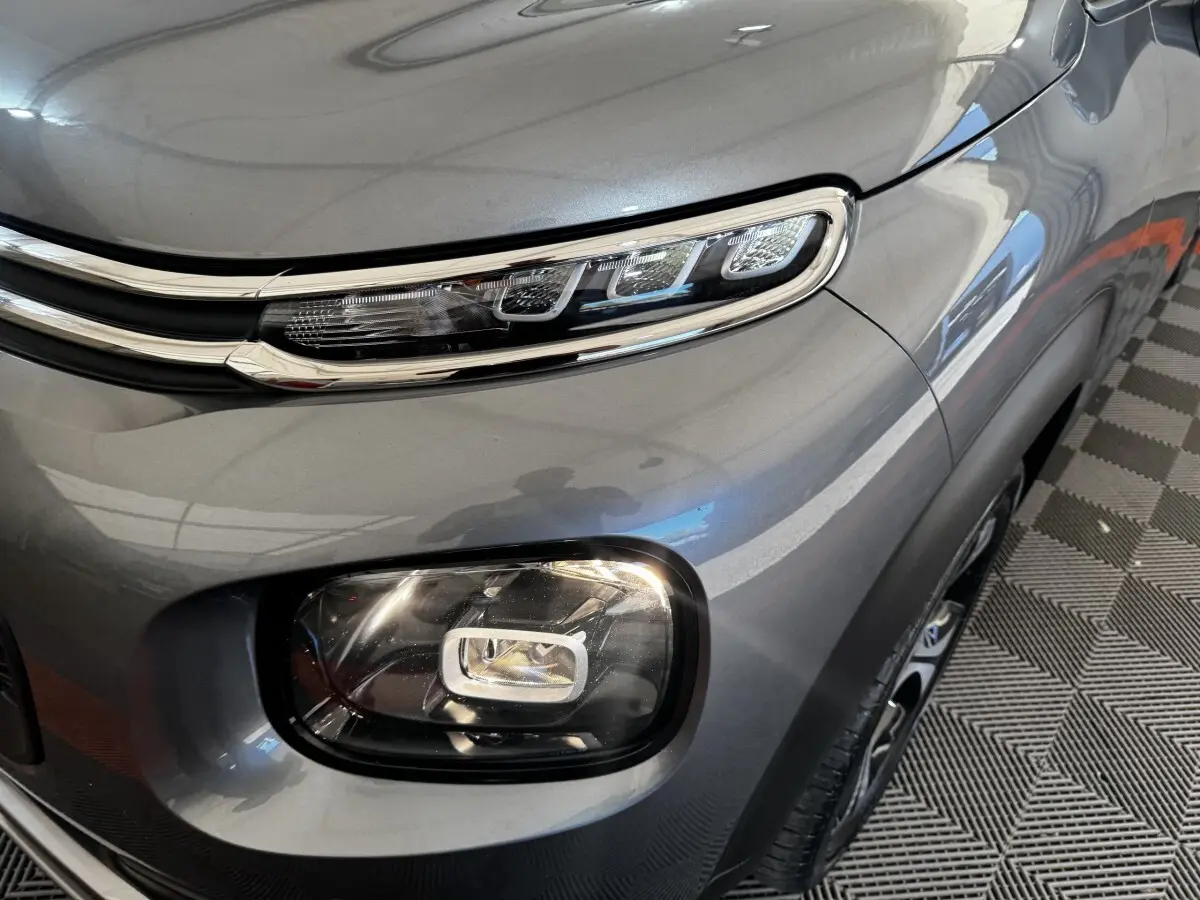 Gros plan sur le phare avant droit gris foncé d’une Citroën C3 PureTech 110 Shine, soulignant ses feux LED distinctifs.