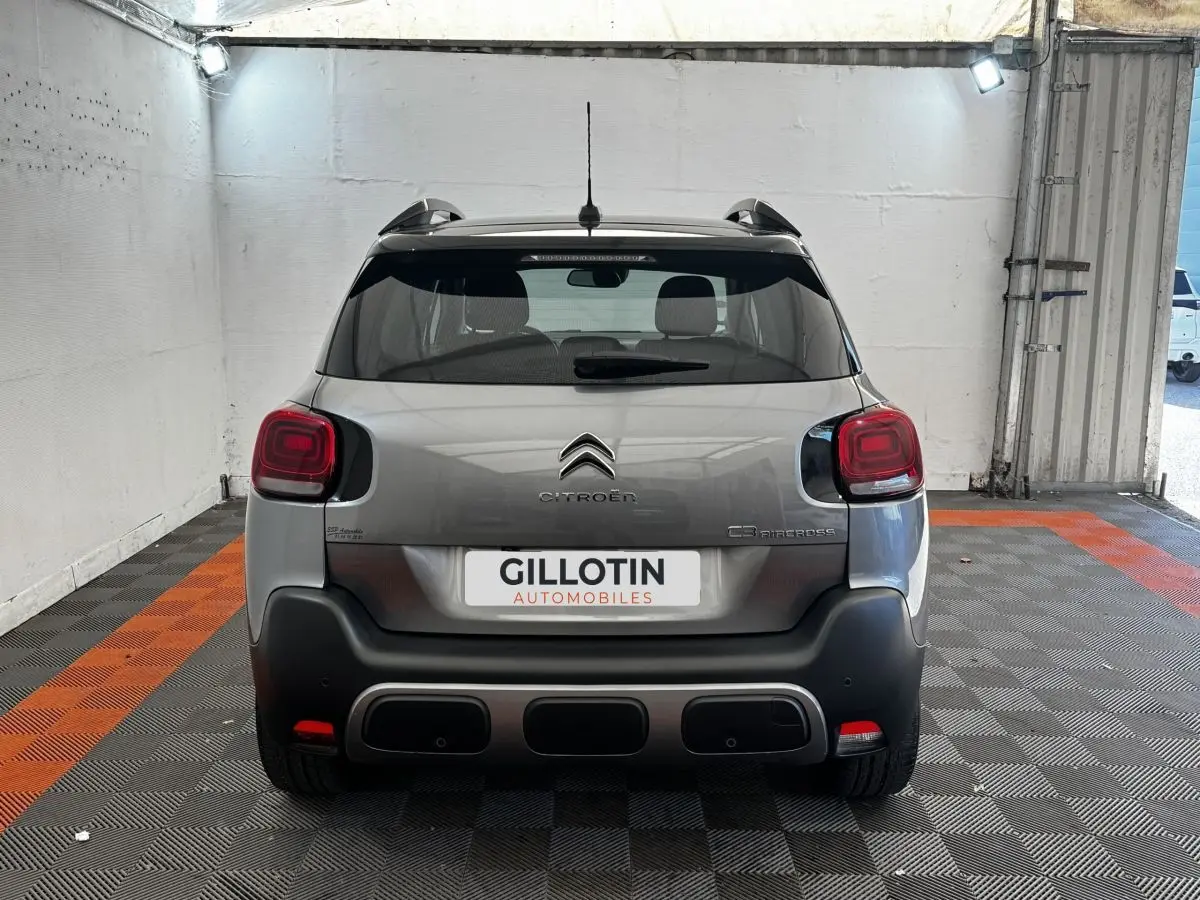 Vue arrière d'une Citroën C3 Aircross gris foncé, stationnée en intérieur sur sol à damier noir et orange.