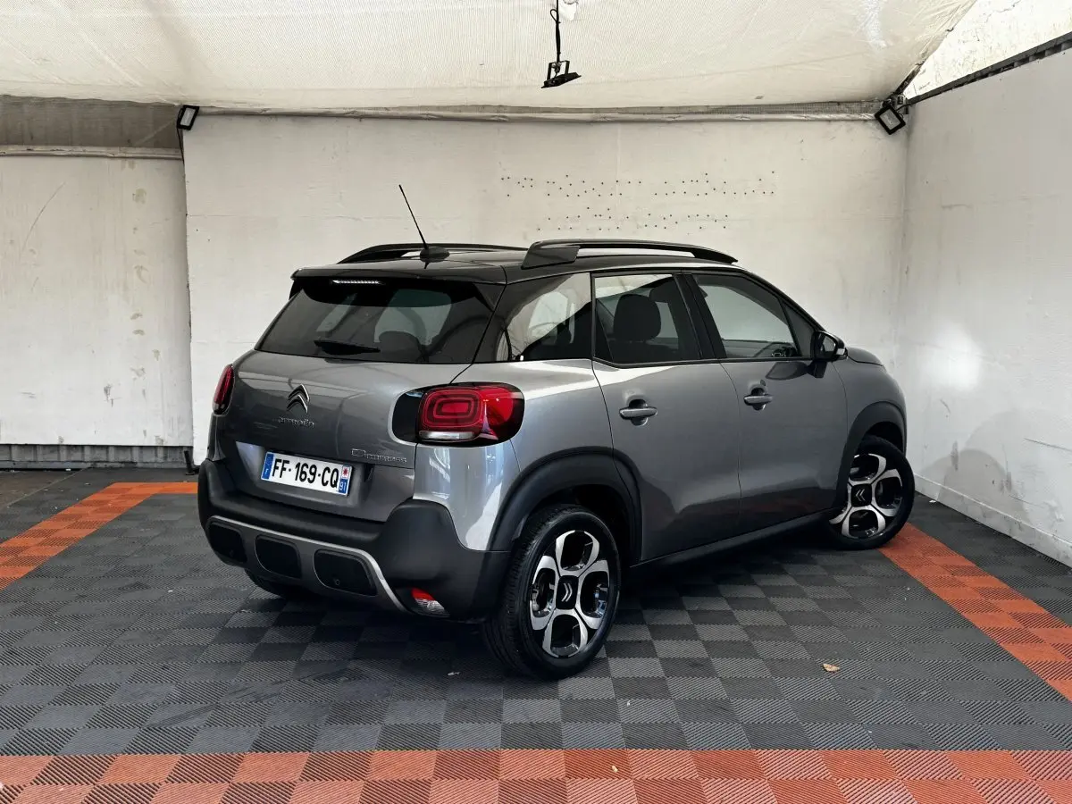 Vue 3/4 arrière droite d'une Citroën C3 gris foncé avec toit noir et jantes distinctives en alliage.