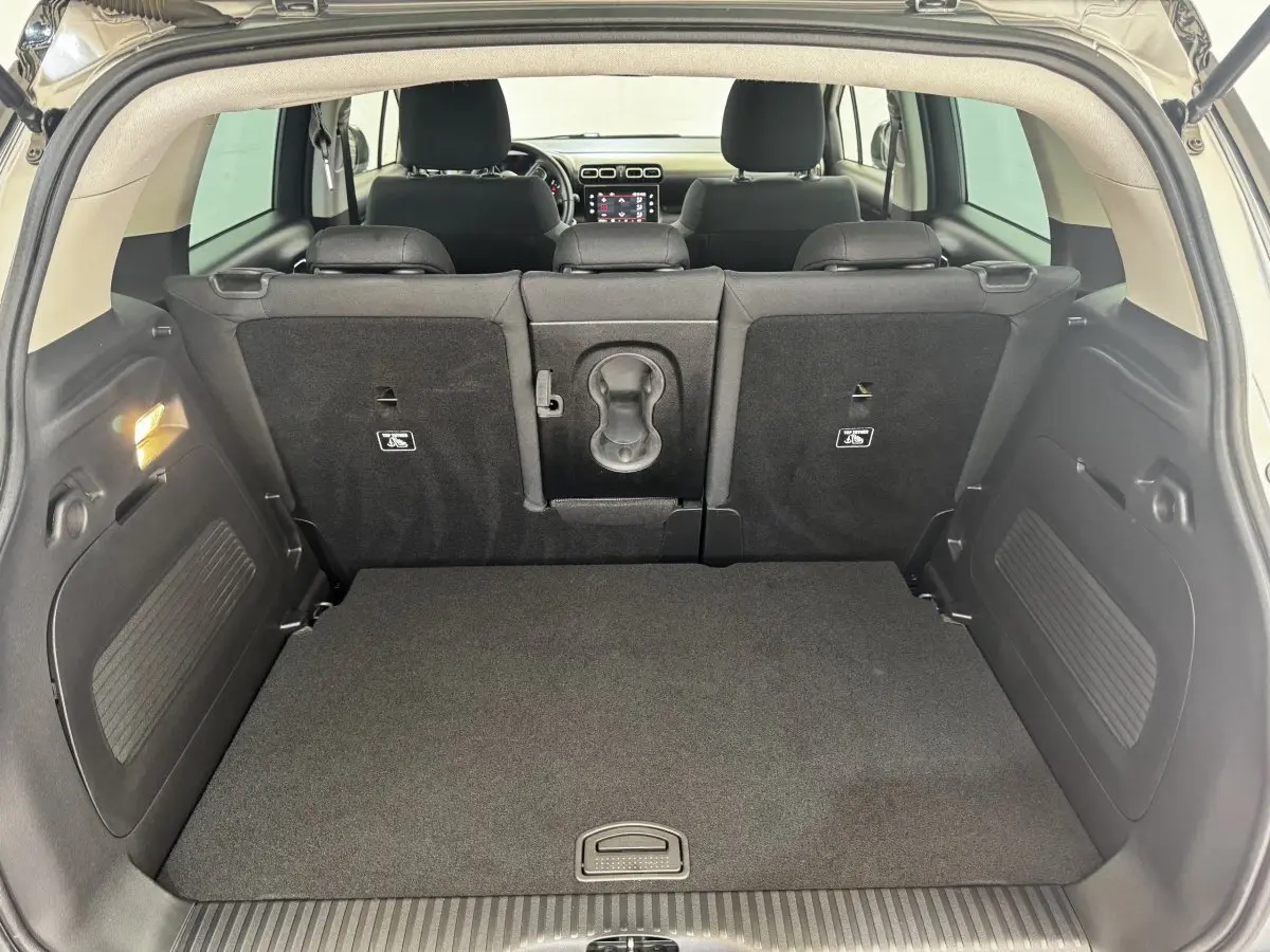 Vue depuis le coffre d'une Citroën C3 gris foncé, montrant la banquette arrière et l'écran tactile du tableau de bord.
