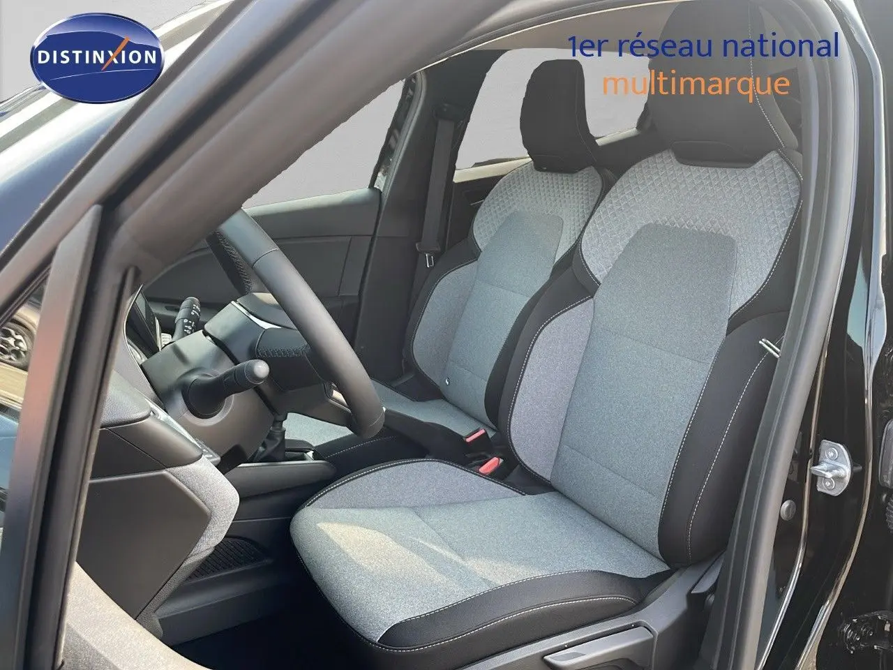 Vue intérieure côté conducteur de la Renault Clio 2025 noire étoile métal, sièges tissu gris clair avec surpiqûres noires.