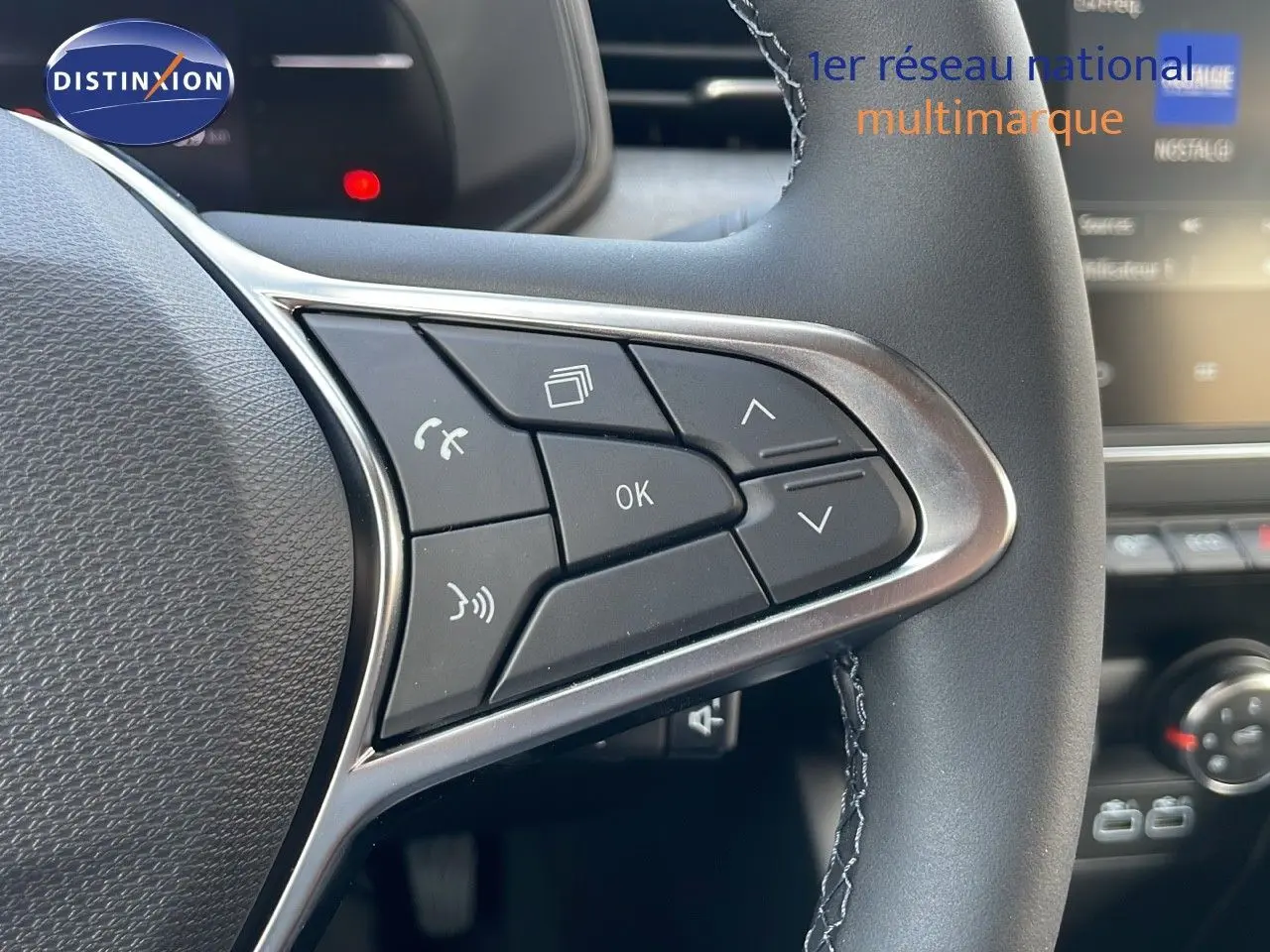 Gros plan sur les commandes multifonctions au volant d'une Renault Clio 1.5 DCI noire, intérieur moderne avec écran tactile visible.